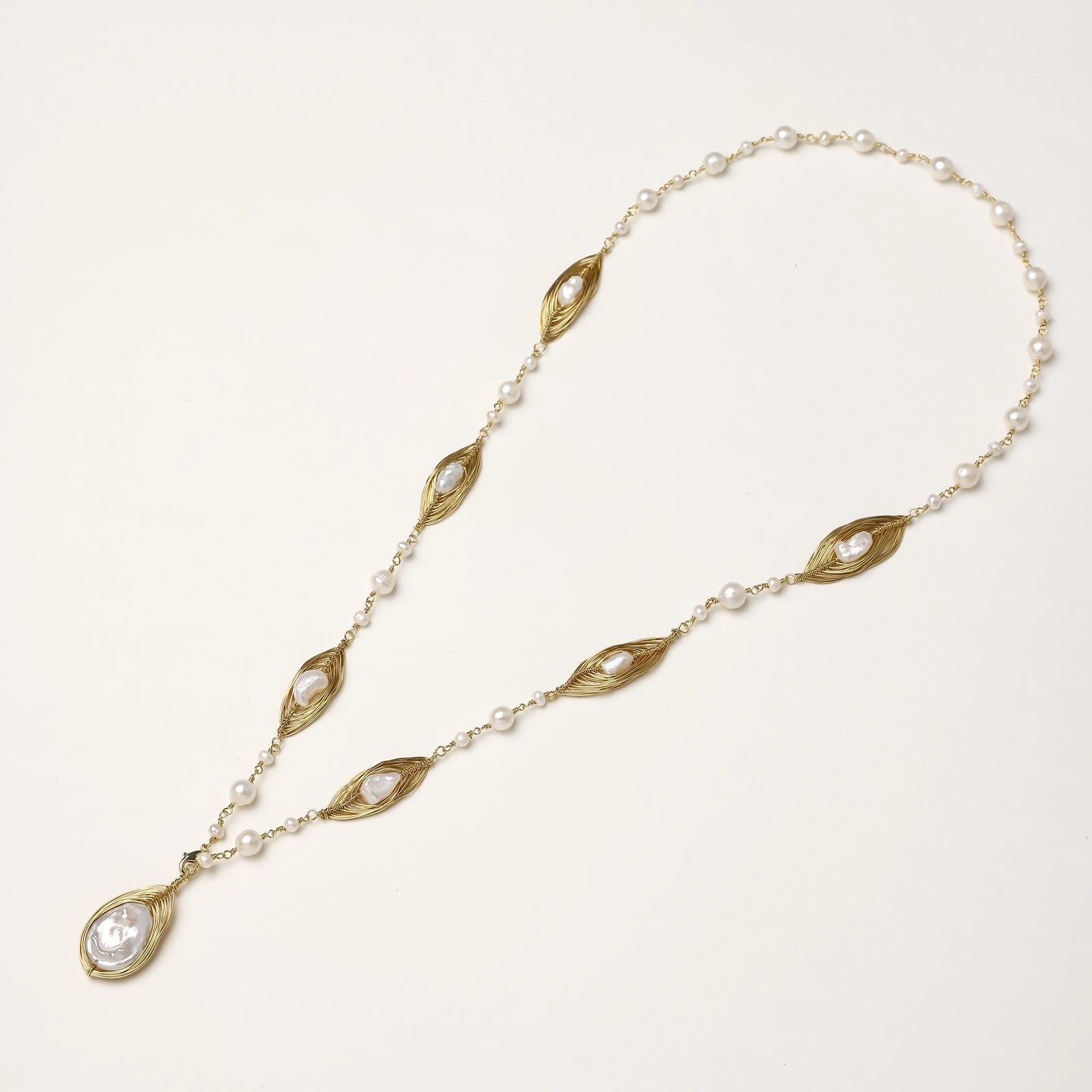 14K gold plated necklace with organic leaf motifs and freshwater pearls arranged in an elegant chain design on neutral background.