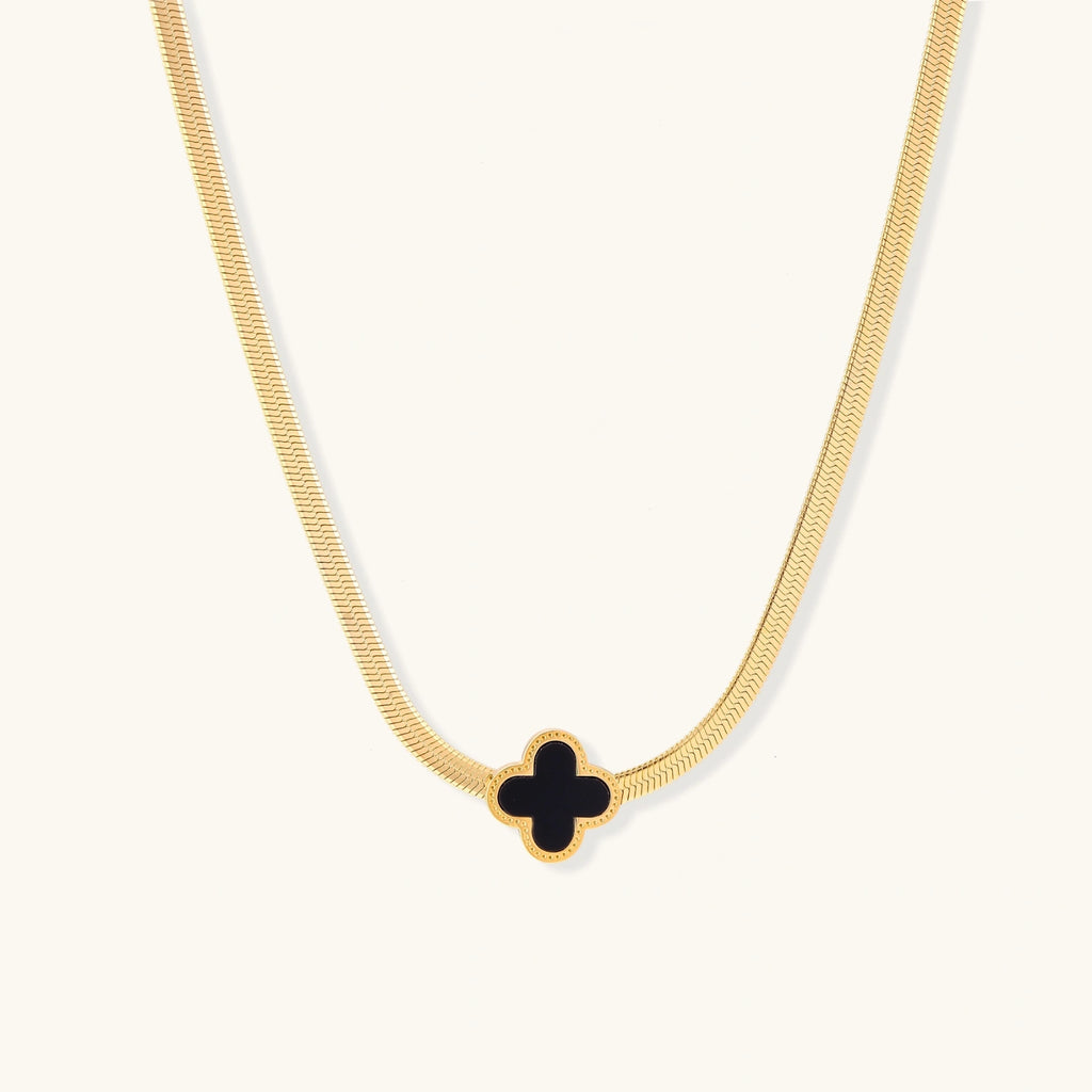 Dainty 18K gold-plated herringbone chain necklace with black enamel quatrefoil clover pendant on white background
