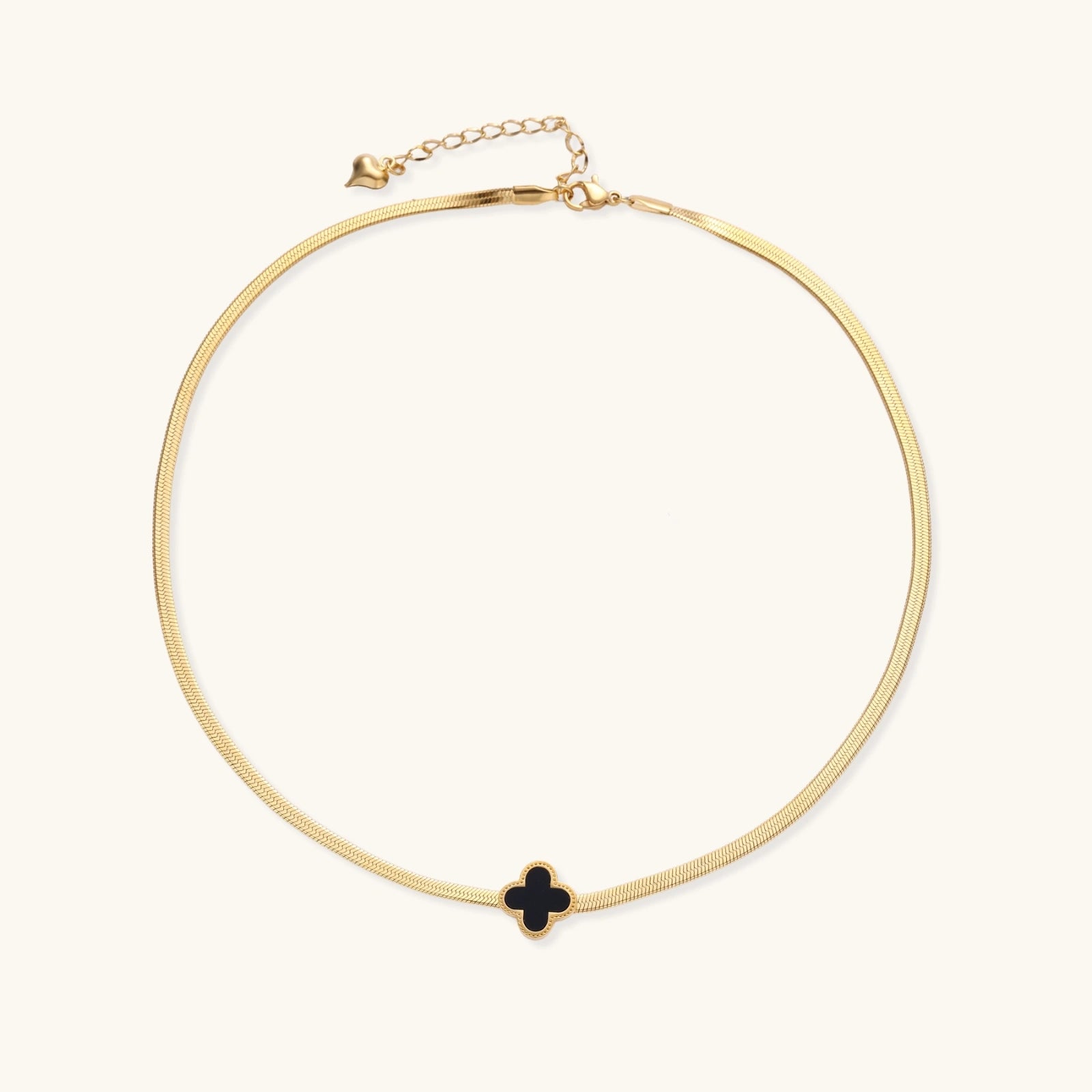 Dainty 18K gold-plated herringbone chain necklace with black enamel quatrefoil clover pendant on white background