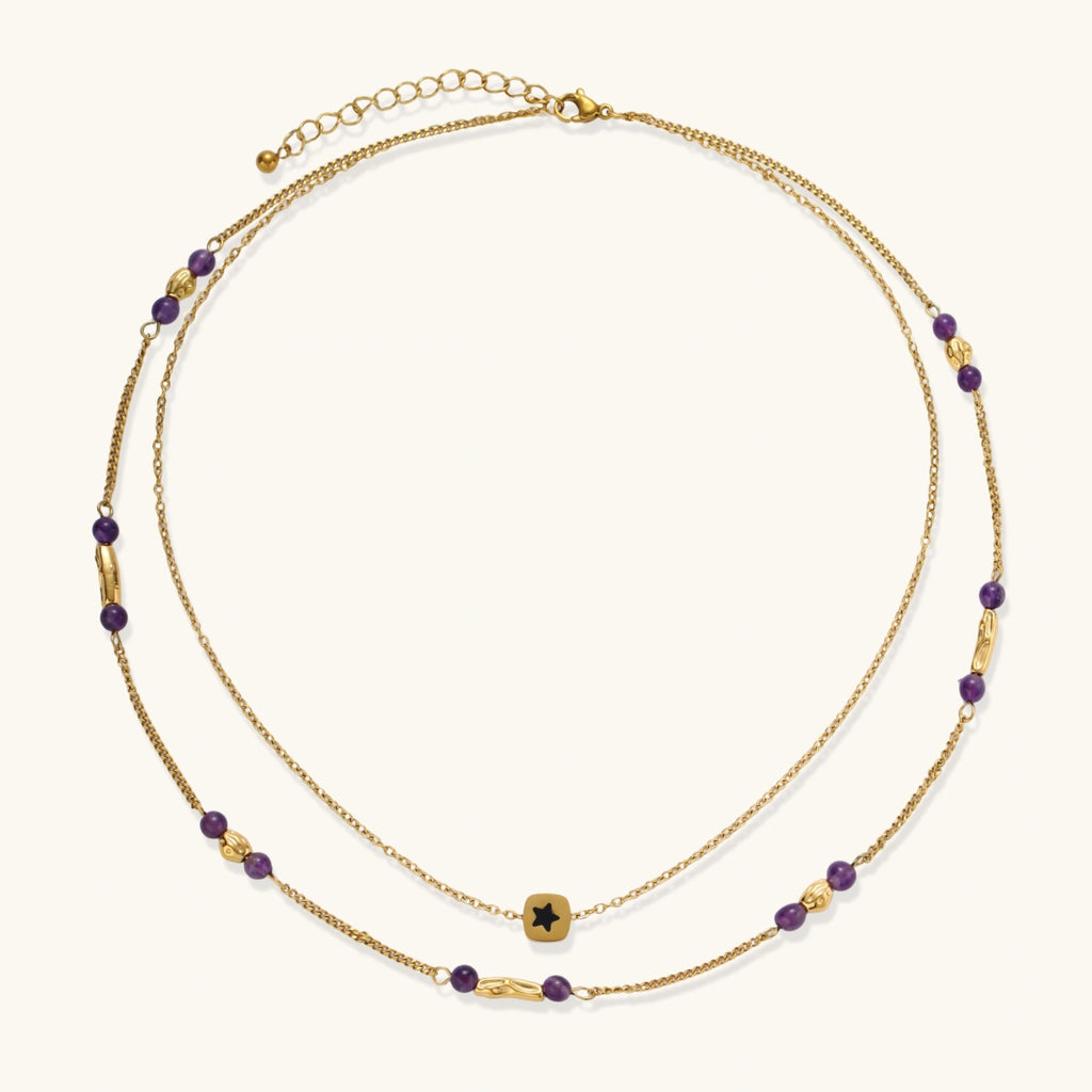 Two layered gold-tone necklaces with purple stone beads and star pendant against cream background.